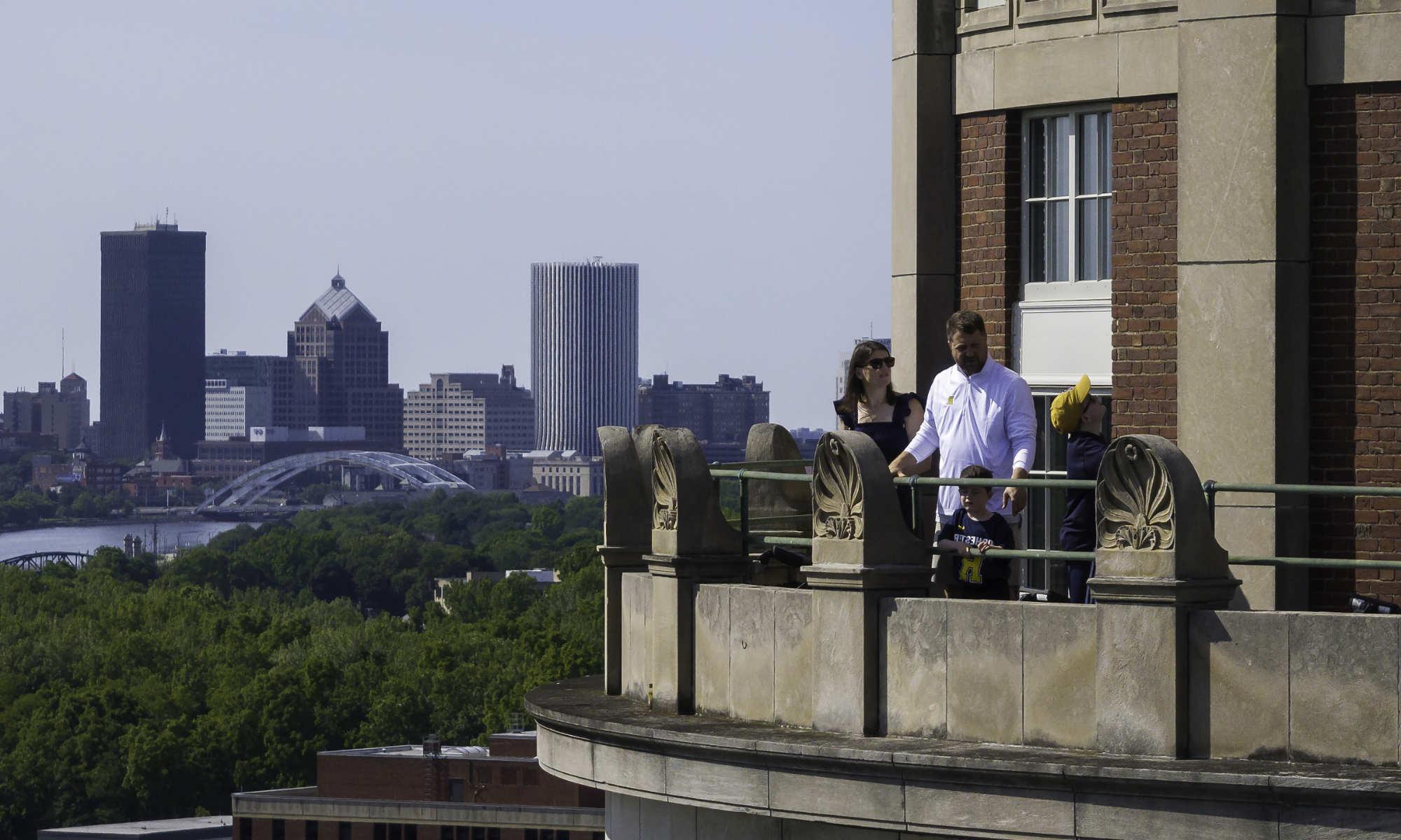 白人, 四口之家, stand on the balcony of the Rush Rhees Library tower with the city of 罗彻斯特 skyline in the background.